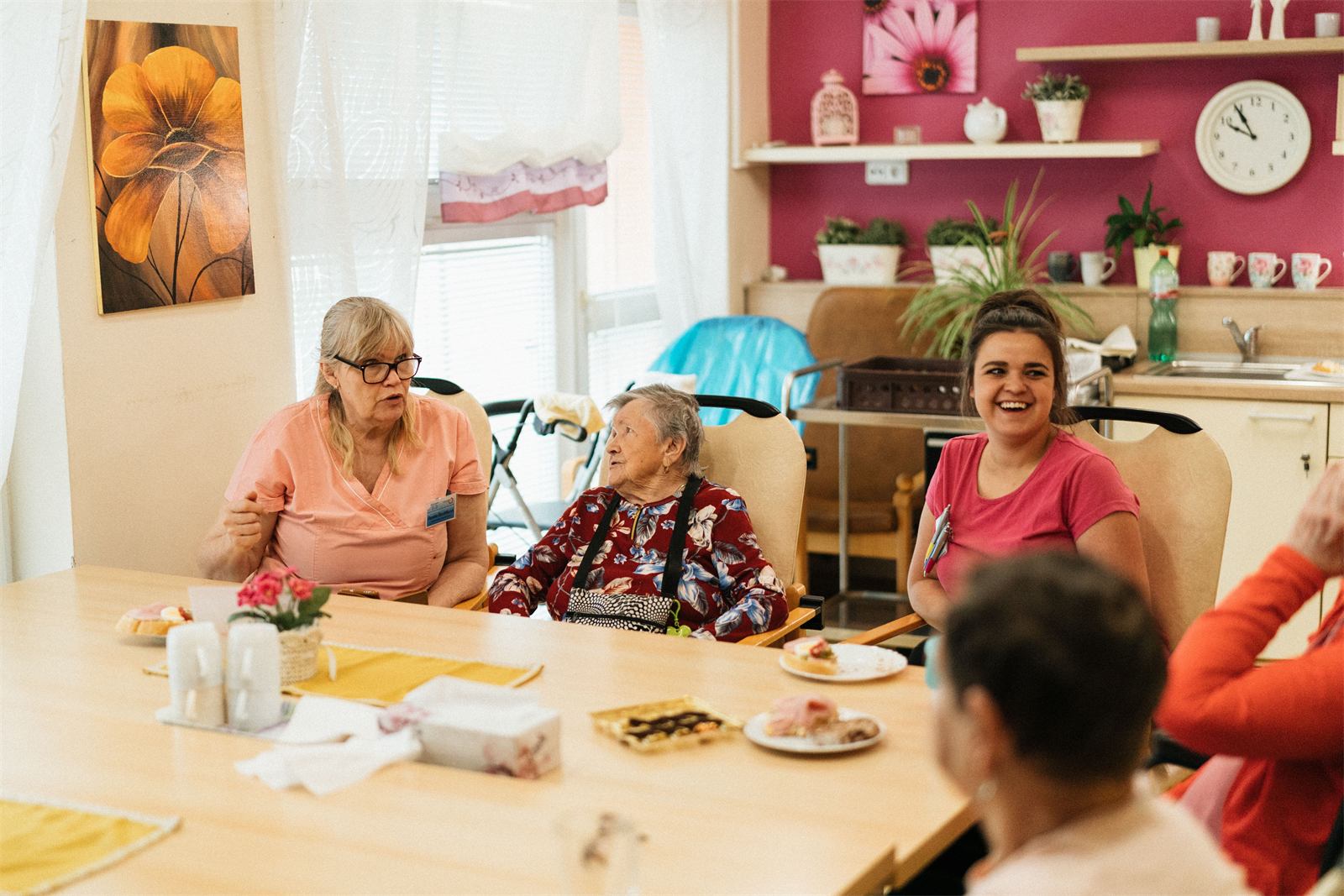 A caregiver and a resident sharing a warm conversation over coffee at a kitchen table.